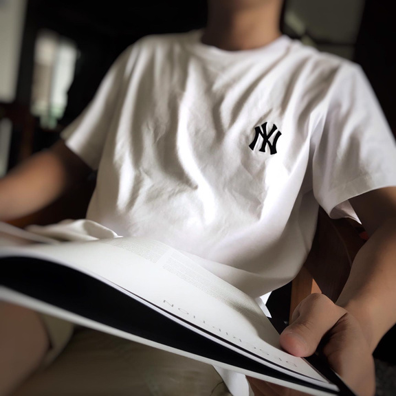 a person wearing a New York Yankees t-shirt is reading a book.