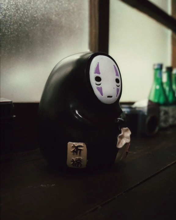 a no face figurine sitting on a table in front of a window